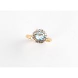 An 18ct yellow gold aquamarine & diamond cluster ring, the round cut aquamarine weighing