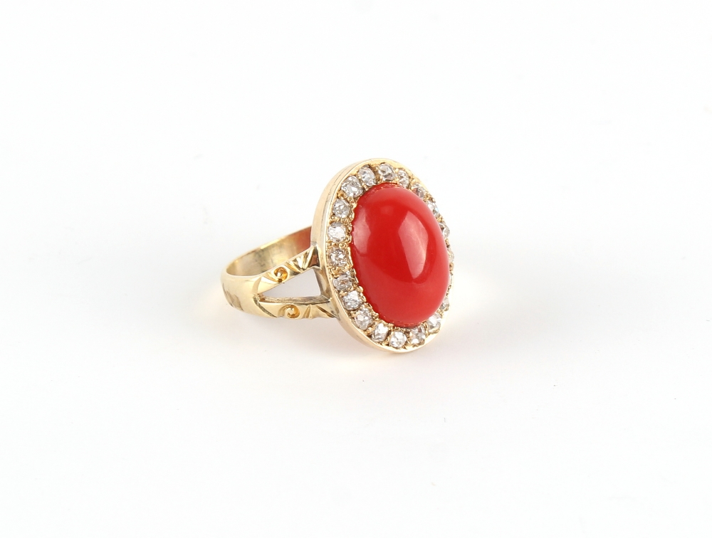 An unmarked yellow gold coral & diamond ring, the oval cabochon coral measuring approximately 19