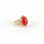 An unmarked yellow gold coral & diamond ring, the oval cabochon coral measuring approximately 19