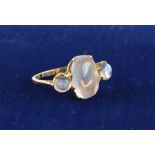 An unmarked high carat yellow gold moonstone three stone ring, the largest moonstone measuring