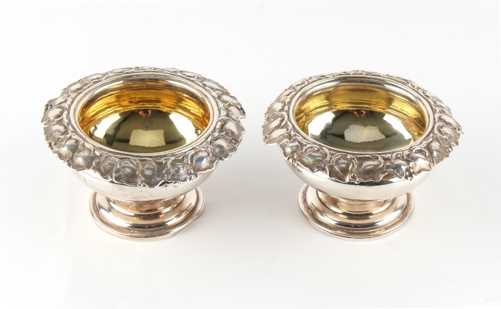 Property of a gentleman - a pair of William IV silver circular pedestal salts with vine borders &
