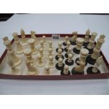 An Ivory Chess Set, circa 1900, the turned pieces on black and white circular bases.