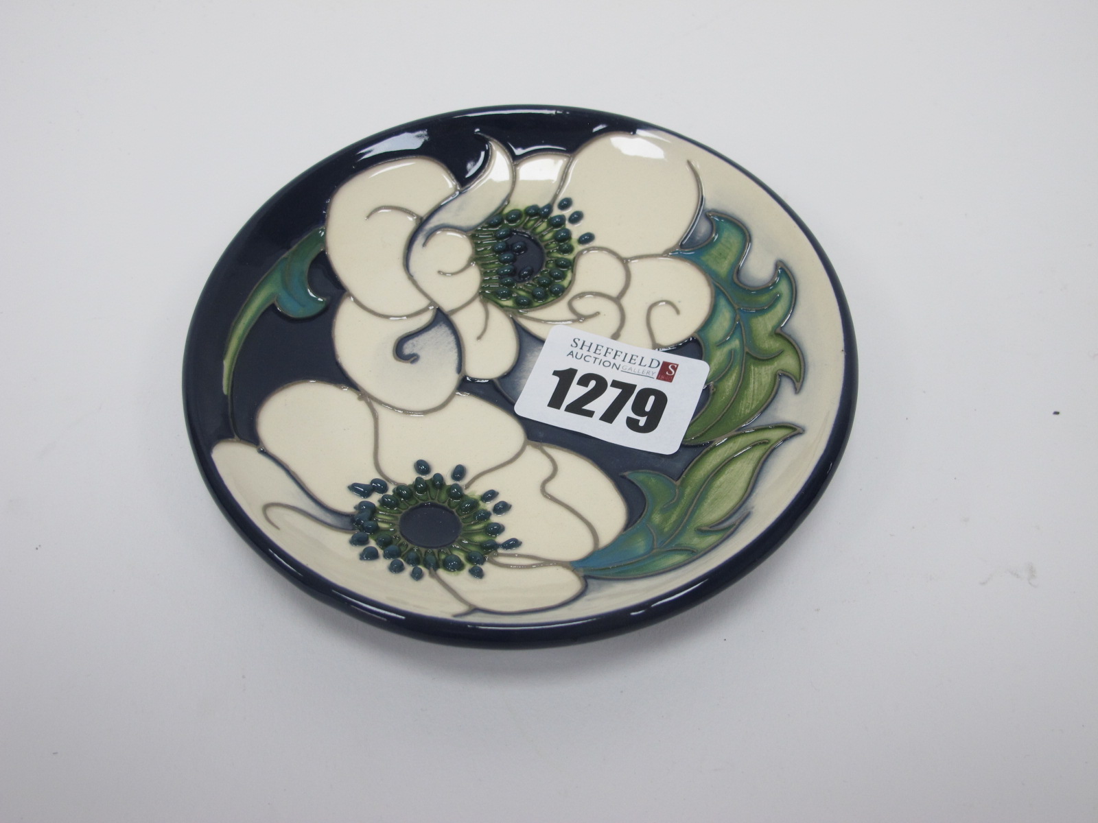 A Moorcroft Pottery Coaster, painted in the Snow Song design by Rachel Bishop, 12cm diameter.