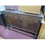 A 1920's Oak Sideboard, with a low back, two small drawers, over twin linen fold doors, on barley