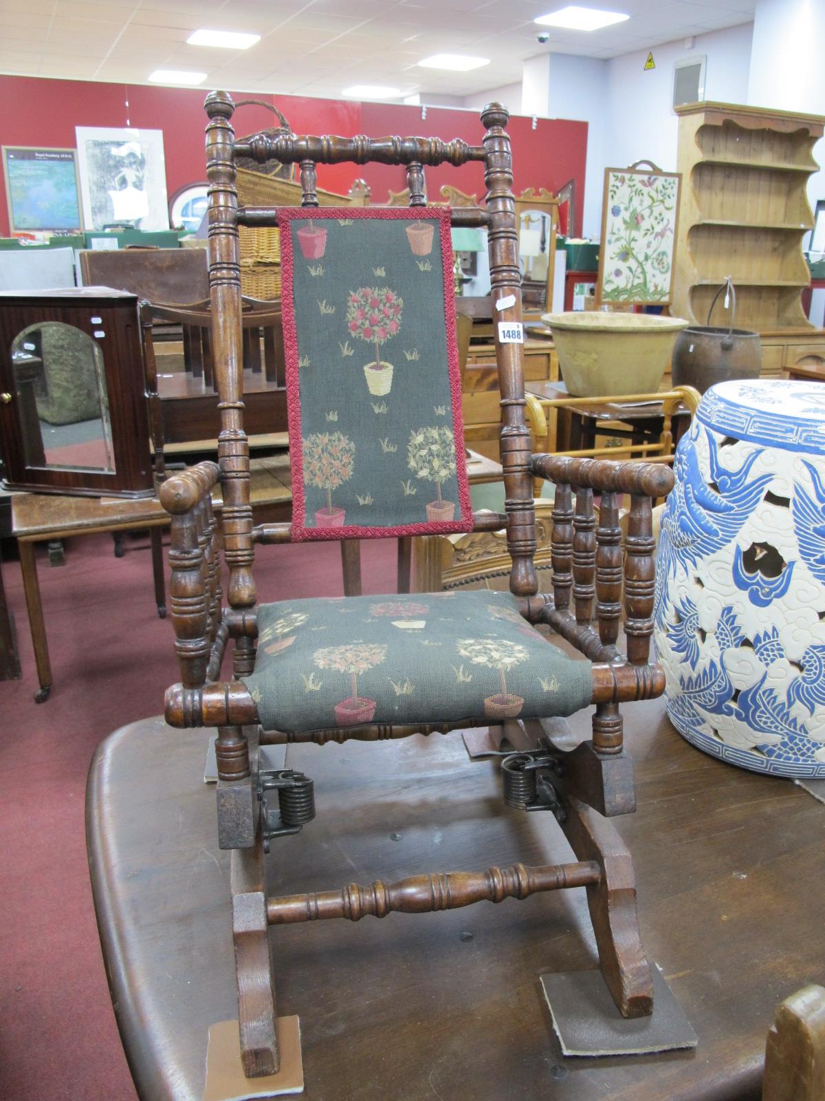 An Edwardian Walnut Child's American Rocker, with turned supports, tree fabric seat and back.