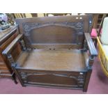 A 1920's Oak Monks Bench, with a sliding top, hinged lid, base with a rose decoration, on stile