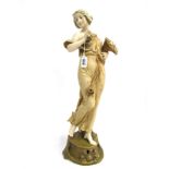 An Ernst Wahliss Austrian Pottery Figure, modelled as a lady carrying a cornucopia of fruit, upon