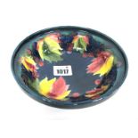 A Moorcroft Pottery Dish, of circular footed form, painted in the Grape and Leaf pattern against a