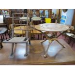 An African Hardwood Coffee Table, with folding tripod base having ethnic bust terminals, 55cm high