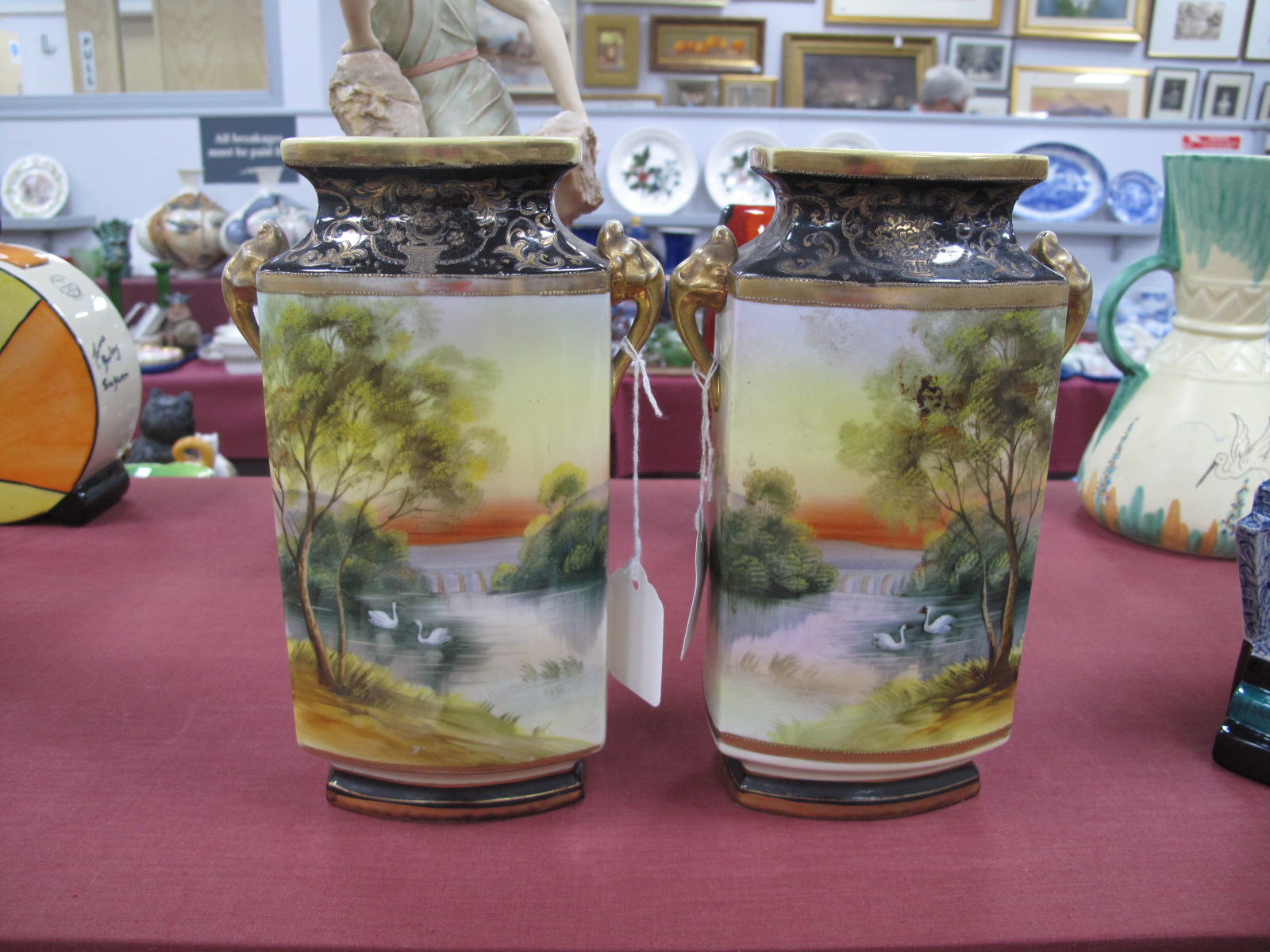 A Pair of Noritake Vases, with landscape scenes, blue and gilt tops and bases, 22cm high.