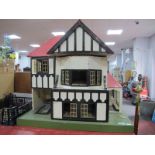 A Child's Dolls House, with red roof, timber fronted, on a green base.