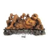 A Chinese Hardwood Late XIX Century Carved Buddha, reclining and holding a bat with five boys