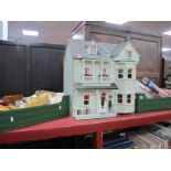 A Dolls House, double fronted, 57.5cm wide; together with conservatory, bed, cot, dresser, three