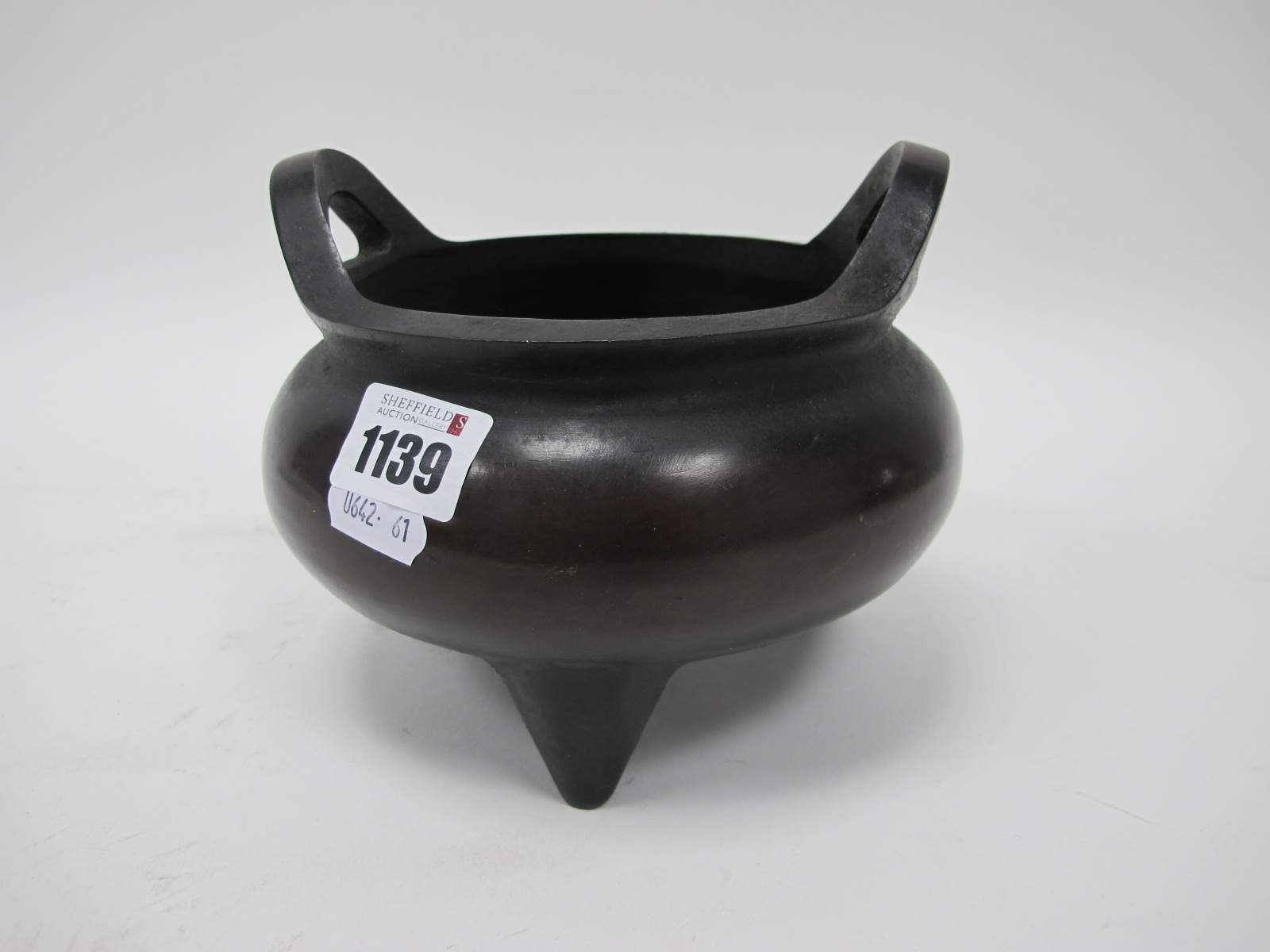 A Chinese Bronze Tripod Censer, of compressed globular form, with twin handles, the base impressed