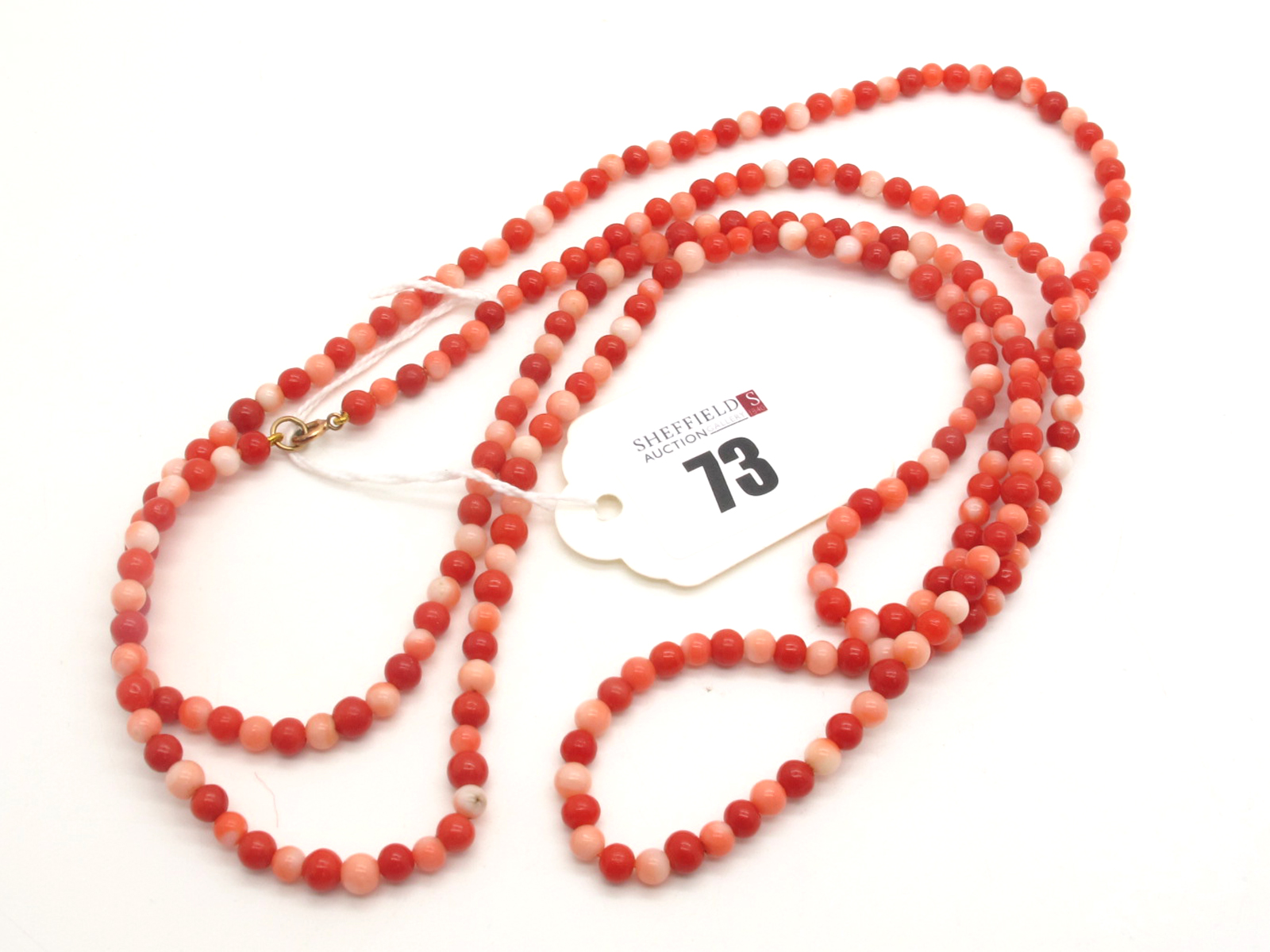 A Long Single Strand Uniform Coral Bead Necklace, varying colour beads, to clasp stamped "9ct".