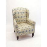 An Edwardian wing armchair upholstered in blue and yellow floral fabric, all on turned supports