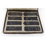 A set of eight Chinese pressed tea bricks or tablets decorated garden scenes and script in fitted
