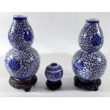 A pair of Chinese blue and white double gourd form vases on stands, 23cm and a smaller one