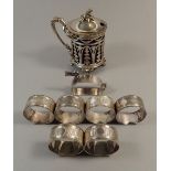 A Victorian silver-plated pierced mustard pot, 'duck' napkin ring and six other napkin rings