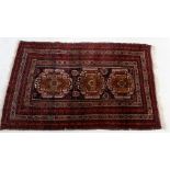 A Turkoman style rug with multiple red borders around two geometric medallions 185 x 118cm