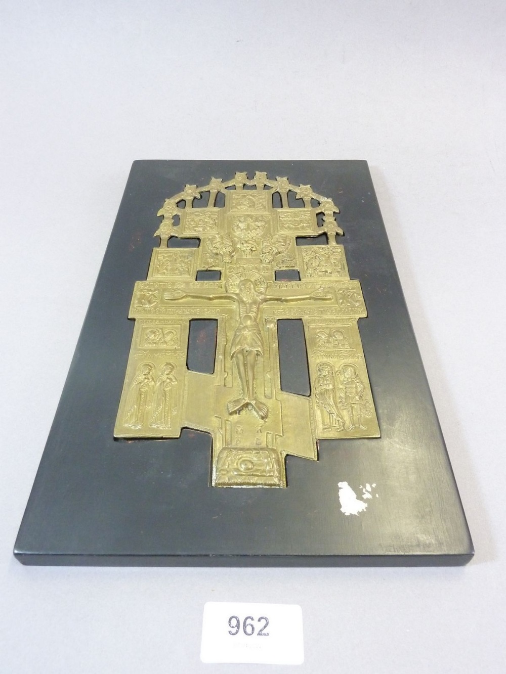 A cast brass icon plaque of Christ on the cross inset into black panel, 31 x 18.5cm