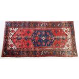 An Afghan style rug with geometric decoration and blue medallion on a red ground, 208 x 104cm