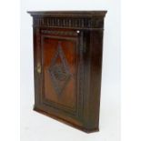 An early 19th century oak corner cabinet with a carved single door