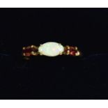 A 9 carat gold ring set opal flanked by two garnets, size N to O, 1.1g