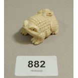 A Japanese ivory Meiji period netsuke of a toad with baby toad to back, signed to base, 4cm long