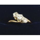 An 18 carat gold three stone diamond crossover ring (unmarked), size L to M, 2.8g