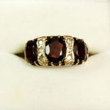 A 9ct gold ring set three garnets and six small diamonds, size K-L