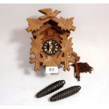 A cuckoo clock with carved decoration and weights
