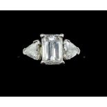 A fine platinum ring set central emerald cut diamond flanked by two trilliant cut diamonds, size