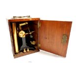An early 20th century brass microscope with movable stage in mahogany case