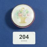 A silver and enamel circular box with basket of flowers to lid, 3.5cm diameter, marked 935, 33g