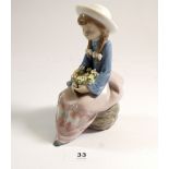 A Lladro figure seated girl with flowers, 15cm tall