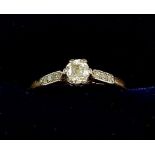 A early 20th century 18ct gold and platinum set solitaire diamond ring on diamond chip shoulders,