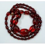An early 20th century string of 'Bakelite' cherry amber approx 90cm total length, largest bead 3.5cm