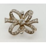 An 18 carat white and yellow gold diamond set ribbon form brooch, 2.5cm x 4cm, 8.5g unmarked