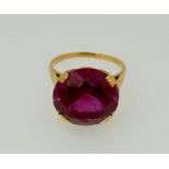 A gold ring set large purple stone - mark worn, 1.5cm diameter, size M