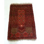 A Turkoman style small prayer rug on a red ground 115 x 77cm