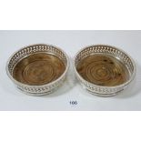 A pair of silver plated bottle coasters on turned wood bases