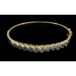 An 18 carat gold hinged bangle with diamond set interlaced panel in white gold, 20g