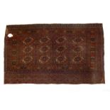 An antique Turkoman rug with three rows of guls on a madder ground - distressed condition with hole,