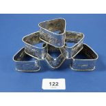 A set of six sterling silver triangular napkin rings with embossed decoration, 59g