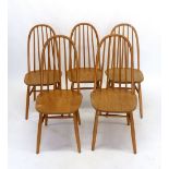 A set of five Ercol style light wood stick back dining chairs