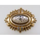 A Victorian yellow metal fronted oval brooch with embossed decoration and set chip diamond