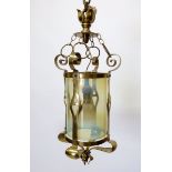 A brass Art Nouveau hall lantern with tendril decoration and vaseline cylindrical glass shade,