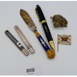 A niello chequer pencil holder and a white metal pencil holder, an enamel handled paper knife a/f,