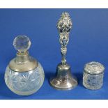 A silver mounted cut glass scent bottle, a silver topped toiletry jar and a silver handled bell